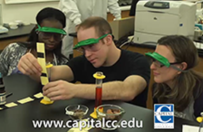 Chemistry Students with safety gogles look at chemistry experiment.